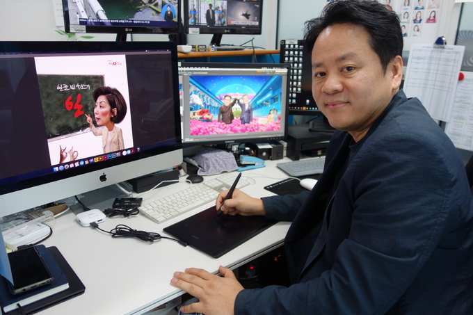 시사 만화가 ‘아트만두’로 활동하고 있는 최재용 YTN 커뮤니케이션팀장을 지난 19일 서울 YTN 뉴스퀘어에서 만났다. 사진은 최 팀장이 자신의 시사 캐리커처를 보여주고 있는 모습. 
